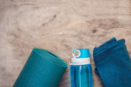 Everything for sports turquoise, blue shades on a wooden background. Yoga mat, sport shoes sportswear and bottle of water. Concept healthy lifestyle, sport and diet. Sport equipment. Copy space.の写真素材