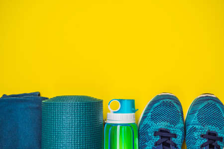 Everything for sports turquoise, blue shades on a yellow background. Yoga mat, sport shoes...