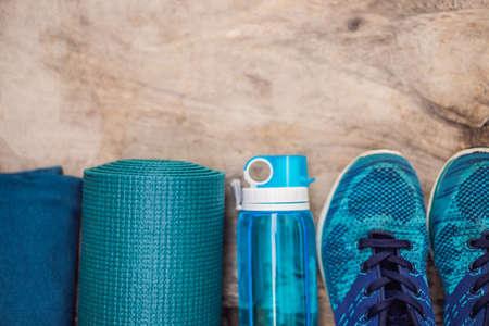 Everything for sports turquoise, blue shades on a wooden background. Yoga mat, sport shoes sportswear and bottle of water. Concept healthy lifestyle, sport and diet. Sport equipment. Copy spaceの写真素材