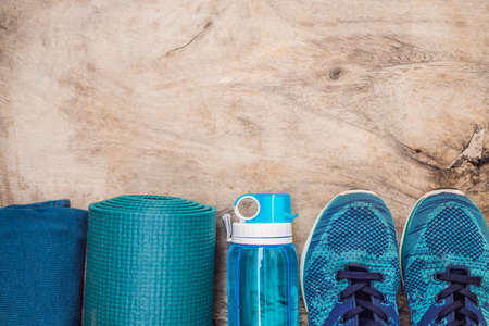 Everything for sports turquoise, blue shades on a wooden background. Yoga mat, sport shoes...