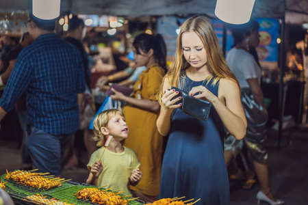 Mom and son are tourists on Walking street Asian food marketの写真素材