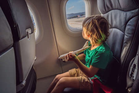 Little boy play with toy plane in the commercial jet airplane flying on vacation