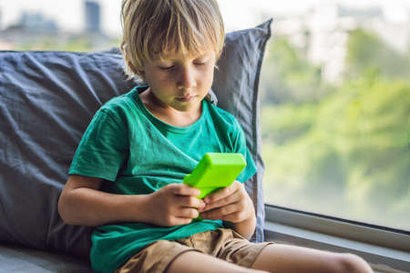 Young boy playing old school portable game console, electronic retro pocket toy with monochrome displayの写真素材