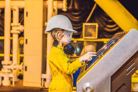 Boy operator recording operation of oil and gas process at oil and rig plant, offshore oil and gas...