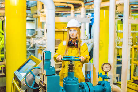 Young woman in a yellow work uniform, glasses and helmet in industrial environment,oil Platform or liquefied gas plantの写真素材