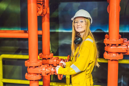 Young woman in a yellow work uniform, glasses and helmet in industrial environment,oil Platform or liquefied gas plantの写真素材