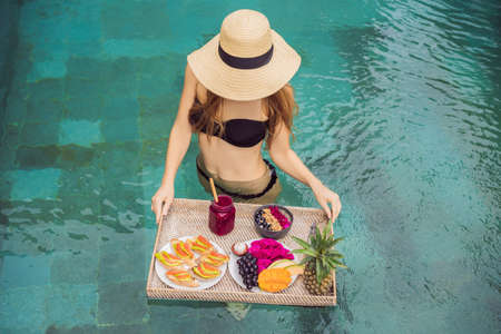 Breakfast tray in swimming pool, floating breakfast in luxury hotel. Girl relaxing in the pool...