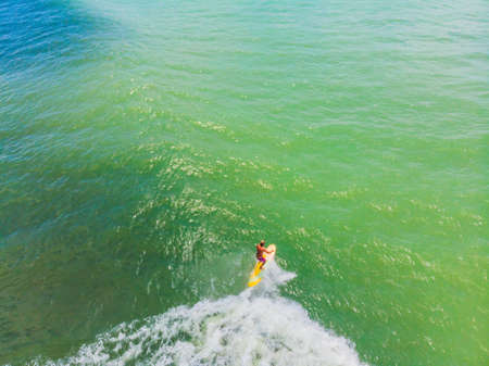 An aerial view of surfers waiting for a wave in the ocean on a clear day