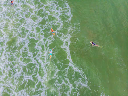 An aerial view of surfers waiting for a wave in the ocean on a clear dayの写真素材