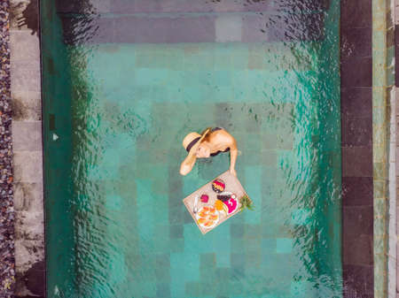 Breakfast tray in swimming pool, floating breakfast in luxury hotel. Girl relaxing in the pool...