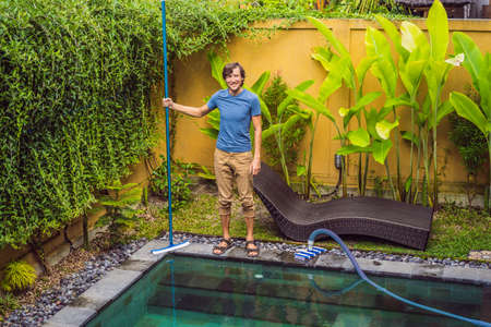 Cleaner of the swimming pool . Man in a blue shirt with cleaning equipment for swimming pools. Pool...