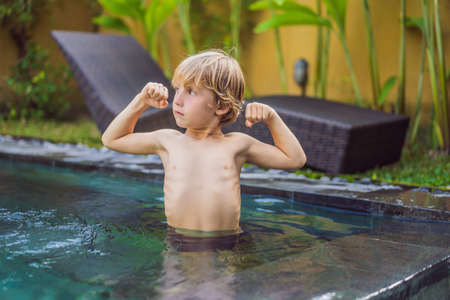 A boy shows his muscles after swimming