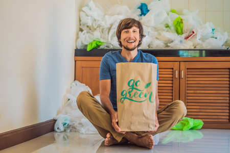 Man holding a package with the inscription GO GREEN amid a pile of plastic bags.の写真素材