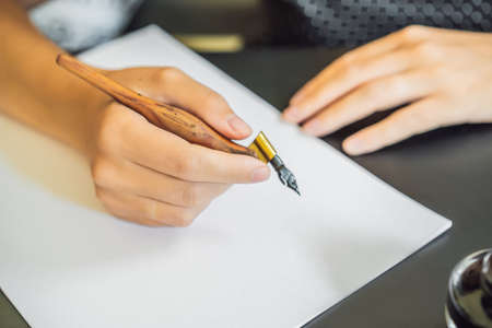 Calligrapher Young Woman writes phrase on white paper. Inscribing ornamental decorated letters. Calligraphy, graphic design, lettering, handwriting, creation conceptの写真素材