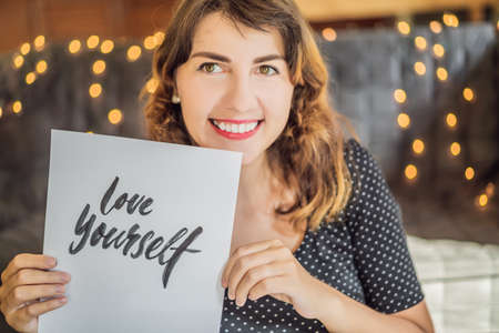 Love yourself. Calligrapher Young Woman writes phrase on white paper. Inscribing ornamental decorated letters. Calligraphy, graphic design, lettering, handwriting, creation conceptの写真素材