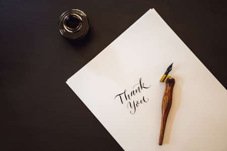 Thank you. Calligrapher Young Woman writes phrase on white paper. Inscribing ornamental decorated...