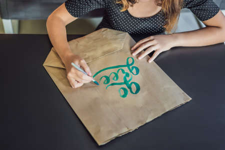 Go green. Calligrapher Young Woman writes phrase on white paper. Inscribing ornamental decorated...