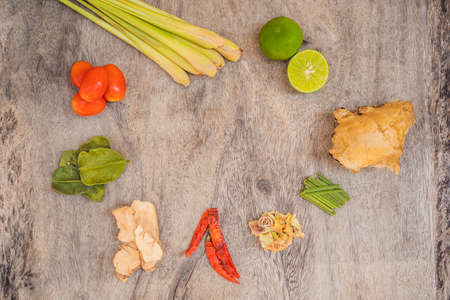 Ingredients for popular Thai soup Tom-yum kung. Lime, galangal, red chili, cherry tomato, lemongrass and kaffir lime leaf on black board . Flat lay. View from aboveの写真素材