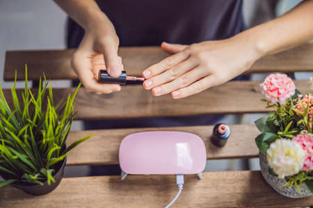 Young woman makes manicure with gel polish and UV lamp in pink shades.の写真素材