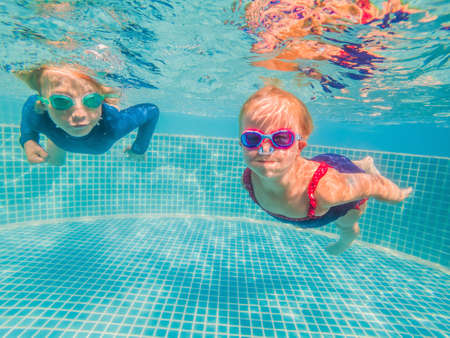 Kids having fun playing underwater in swimming pool on summer vacationの写真素材
