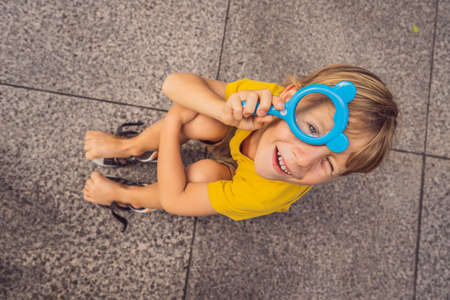 Boy sits on the floor and looks into a magnifying glassの写真素材