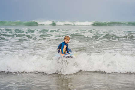 Father or instructor teaching his 5 year old son how to surf in the sea on vacation or holiday....