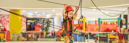 Adorable little boy enjoying his time in climbing adventure park in the mall BANNER, LONG FORMAT