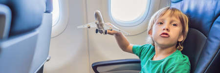 Little boy play with toy plane in the commercial jet airplane flying on vacation BANNER, LONG FORMATの写真素材