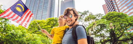 Dad and son tourists in Malaysia with the flag of Malaysia near the skyscrapers. Traveling with kids...
