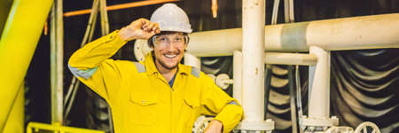 Young man in a yellow work uniform, glasses and helmet in industrial environment,oil Platform or liquefied gas plant BANNER, LONG FORMATの写真素材