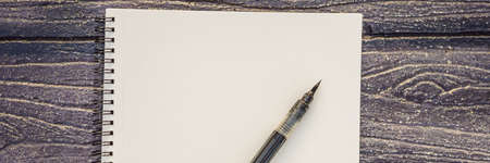 Women's hands in a wooden background holding a signboard, drawing block, paper, mockup. BANNER, LONG FORMATの写真素材