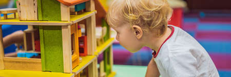 Boy playing with a wooden house from wooden cubes BANNER, LONG FORMATの写真素材