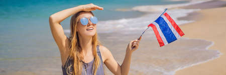 Happy woman having fun at the beach with Thailand flag. Beautiful girl enjoying travel to Asia...
