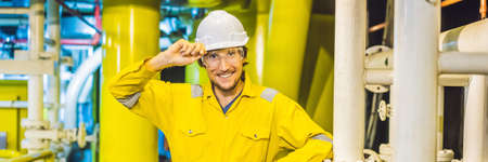 Young man in a yellow work uniform, glasses and helmet in industrial environment,oil Platform or liquefied gas plant BANNER, LONG FORMATの写真素材