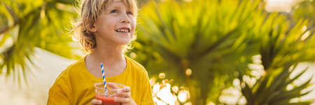 Boy drink healthy smoothies against the backdrop of palm trees. Watermelon smoothies. Healthy...