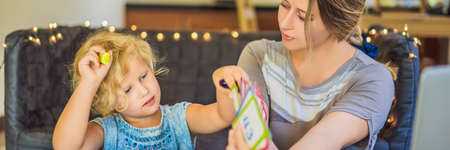 A teacher, a tutor for home schooling and a teacher at the table. Or mom and daughter. Homeschooling BANNER, LONG FORMATの写真素材