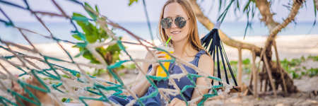 Young woman on the beach in a hammock with a drink BANNER, LONG FORMATの写真素材