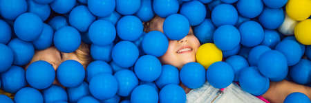 BANNER, LONG FORMAT Child playing in ball pit. Colorful toys for kids. Kindergarten or preschool play room. Toddler kid at day care indoor playground. Balls pool for children. Birthday party for active preschoolerの写真素材