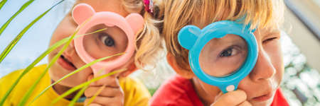 Boy and girl are looking in a magnifying glass against the background of the garden. Home schooling...
