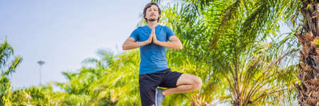 Man doing yoga in a tropical park BANNER, LONG FORMATの写真素材