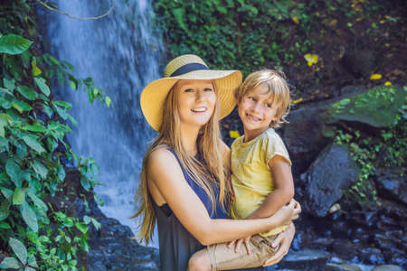 Mom and son tourists on the background of a waterfall. Traveling with kids concept. What to do with children Children friendly placeの写真素材