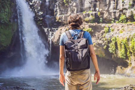 Man traveler on a waterfall background. Ecotourism concept