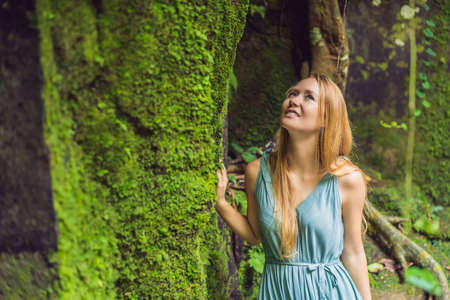 Young woman traveler in a Balinese garden overgrown with moss. Travel to Bali concept