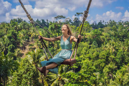 Young woman swinging in the jungle rainforest of Bali island, Indonesia. Swing in the tropics. Swings - trend of Baliの写真素材