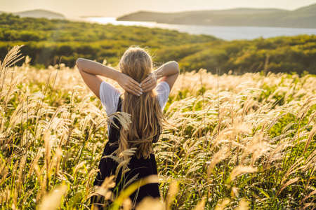 Young beautiful woman in autumn landscape with dry flowers, wheat spikes. Fashion autumn, winter....