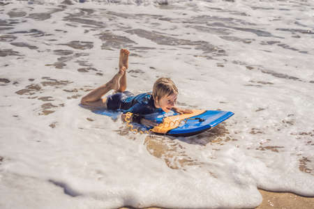 Happy Young boy having fun at the beach on vacation, with Boogie boardの写真素材