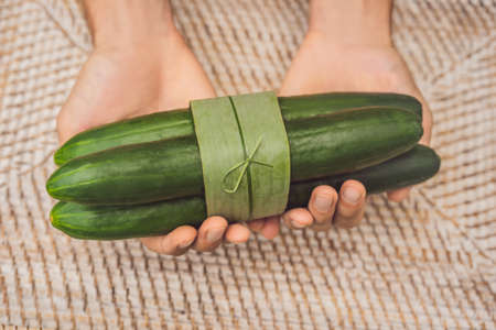 Eco-friendly product packaging concept. Cucumber wrapped in a banana leaf, as an alternative to a plastic bag. Zero waste concept. Alternative packagingの写真素材