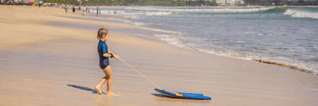 Happy Young boy having fun at the beach on vacation, with Boogie boardの写真素材