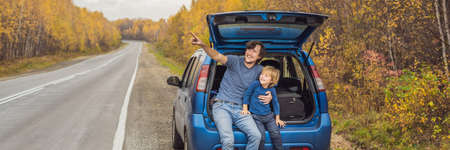 Dad and son are resting on the side of the road on a road trip.の写真素材