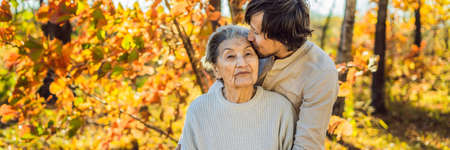 Grandmother and adult grandson hugging in autumn park BANNER, LONG FORMATの写真素材